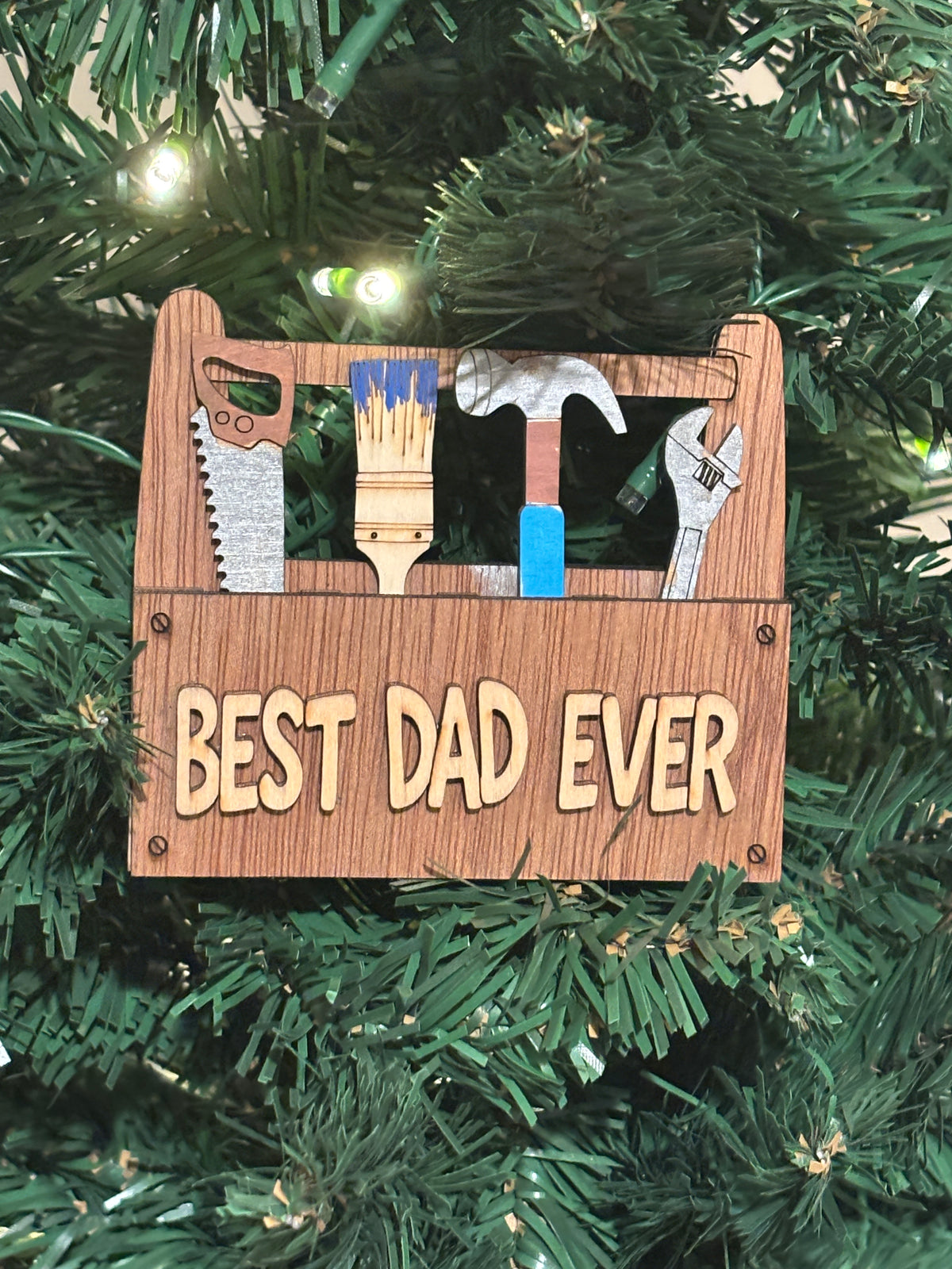 This "Best Dad Ever" toolbox has a lot of personality.
The miniature tools are Removable. 
It has 2 strong magnets and a hanger recessed in the back and also comes with the perfect sized easel. 
This item can be personalized making it a great for man or a woman. 

 Handcrafted • Dimensional • Unique 3D Design
The tools are Removable Tools - Take them out and switch the positions if you choose. 

They're not a printed Design on a flat piece wood.
