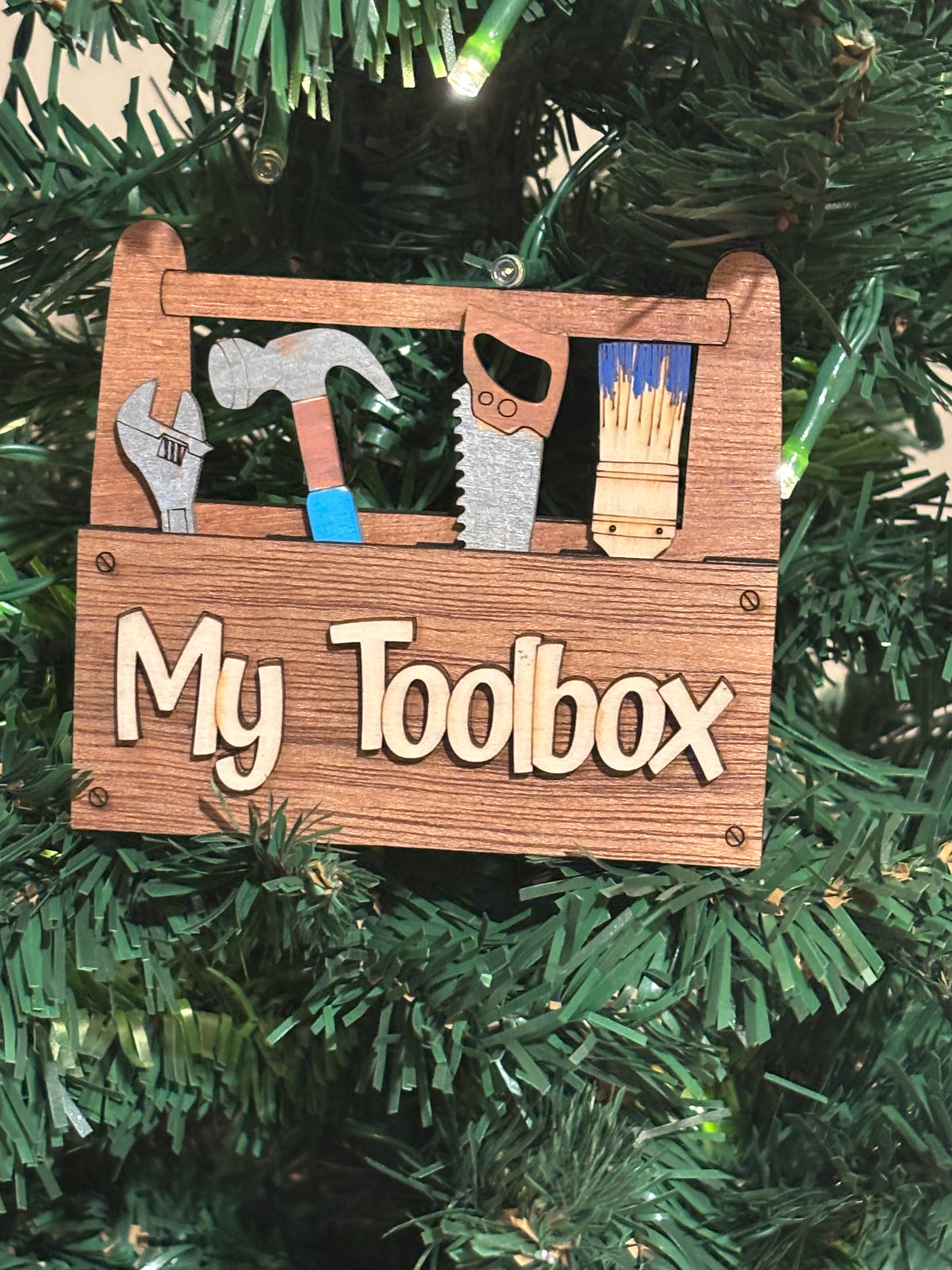 This is a view of the "My Toolbox."
This item is shown here on a Christmas Tree. It has 2 Strong Magnets and a Hanger on the back. It also comes with a perfectly sized easel.  
 3d Unique design, Handcrafted, this item is not printed. Its laser engraved and precision cut. 
The tools are removable and can be replaced in any slot you wish.

This item measures approximately 3.5" X 4.0 inches.